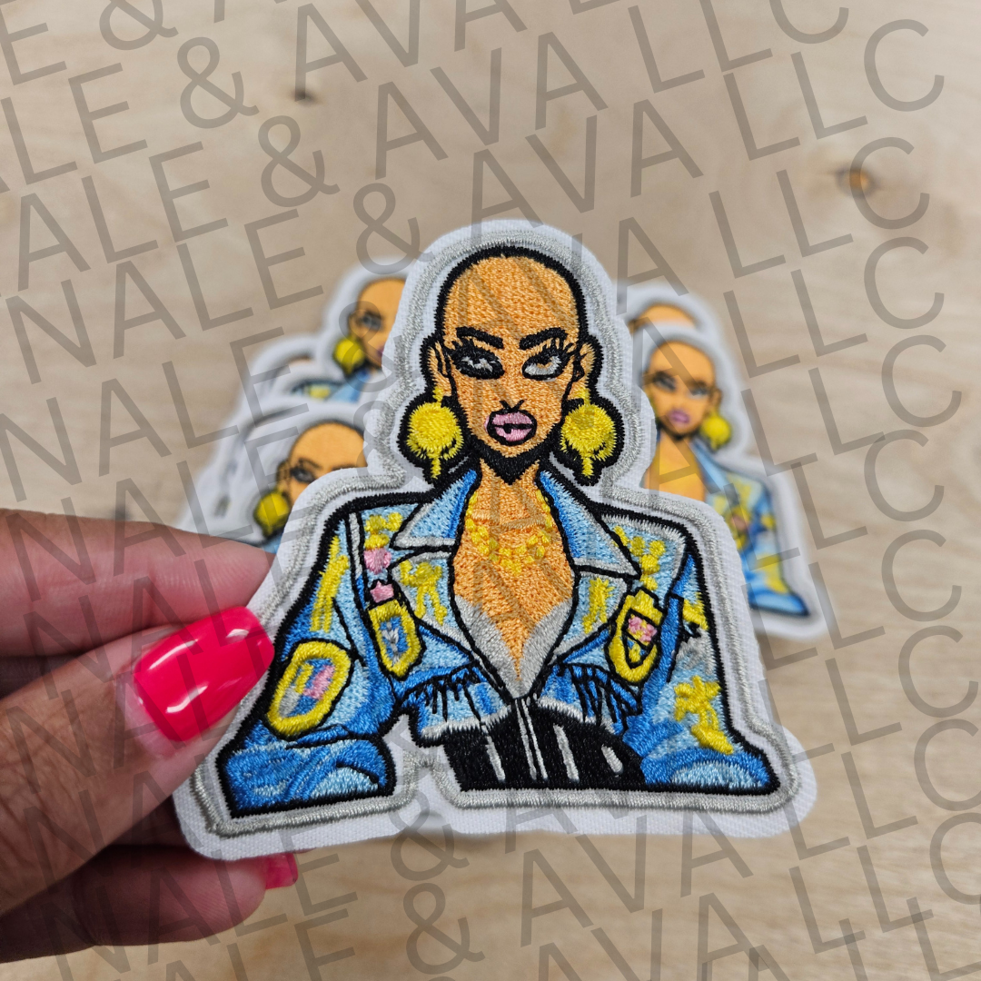 Patch of a stylized character with a blue jacket held by a hand against a branded background.