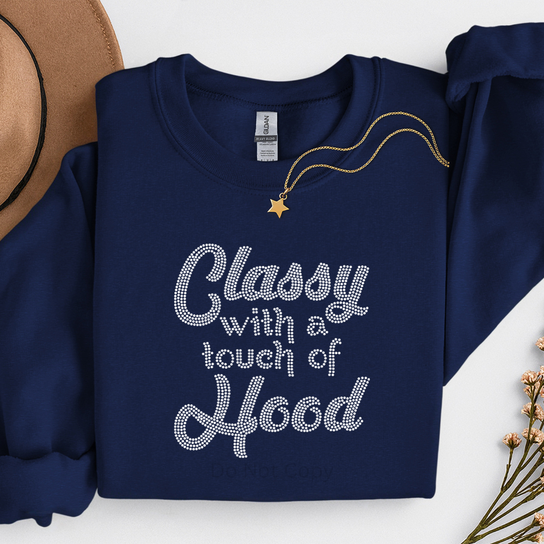 Navy blue sweatshirt with 'Classy with a touch of Hood' text, necklace, and hat on a white background