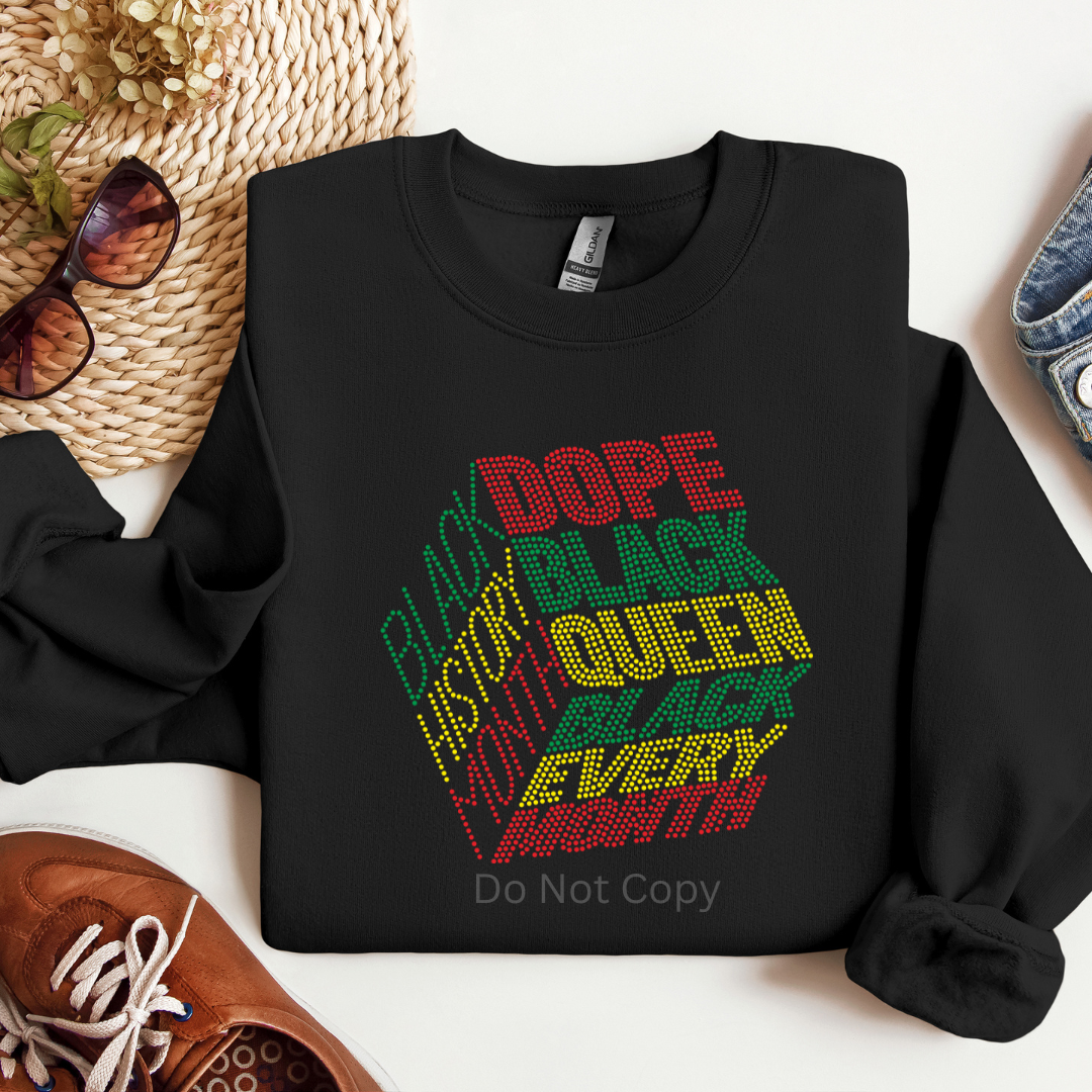 Black sweatshirt with colorful text design on a white surface with accessories around.