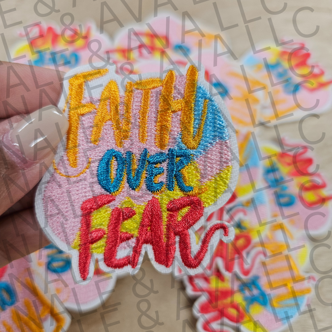 Colorful patch with 'Faith Over Fear' text held by a hand on a multicolored background.