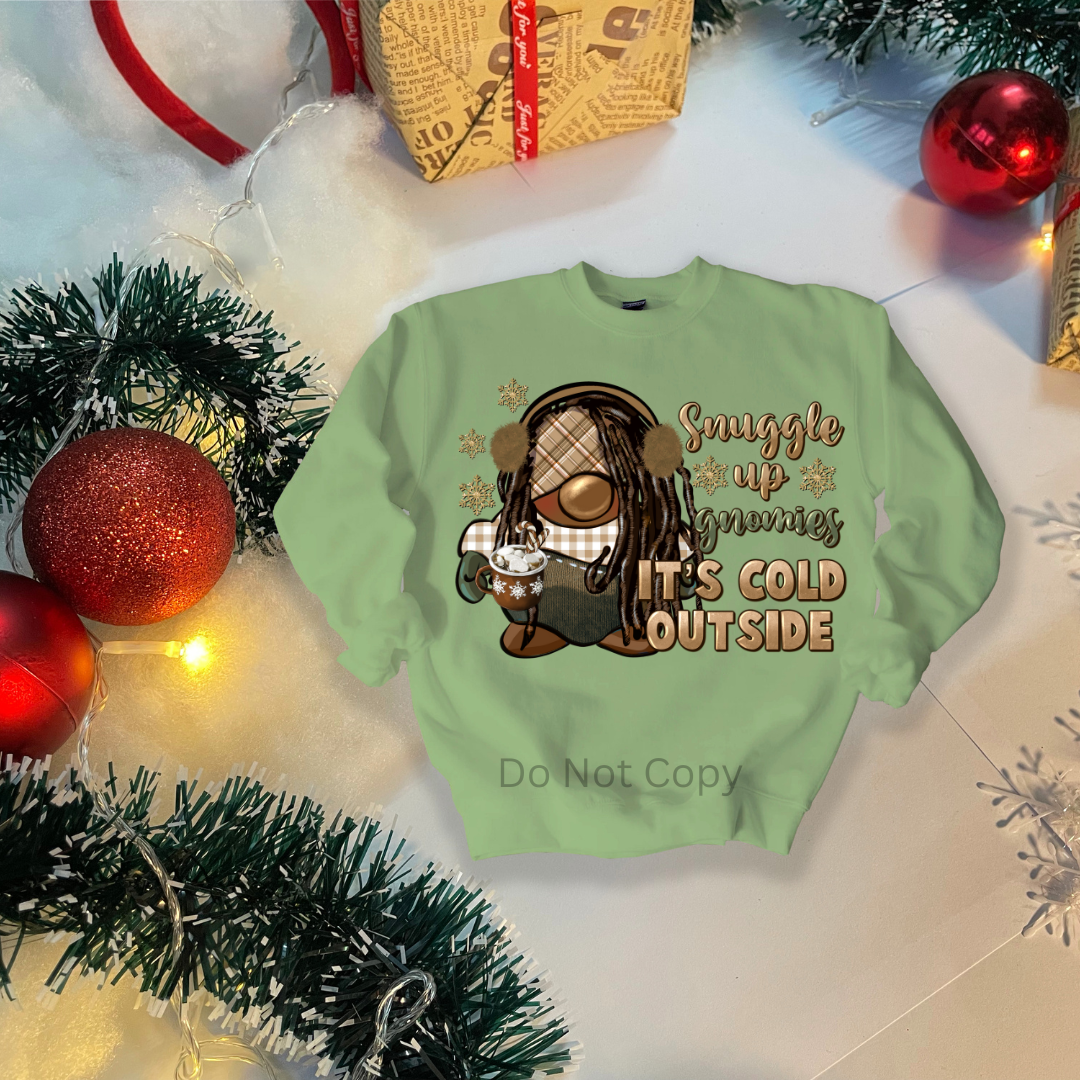 A green colored garment with a printed transfer design depicting a gnome and the phrase 'Snuggle up Gnomies, It's Cold Outside.'.