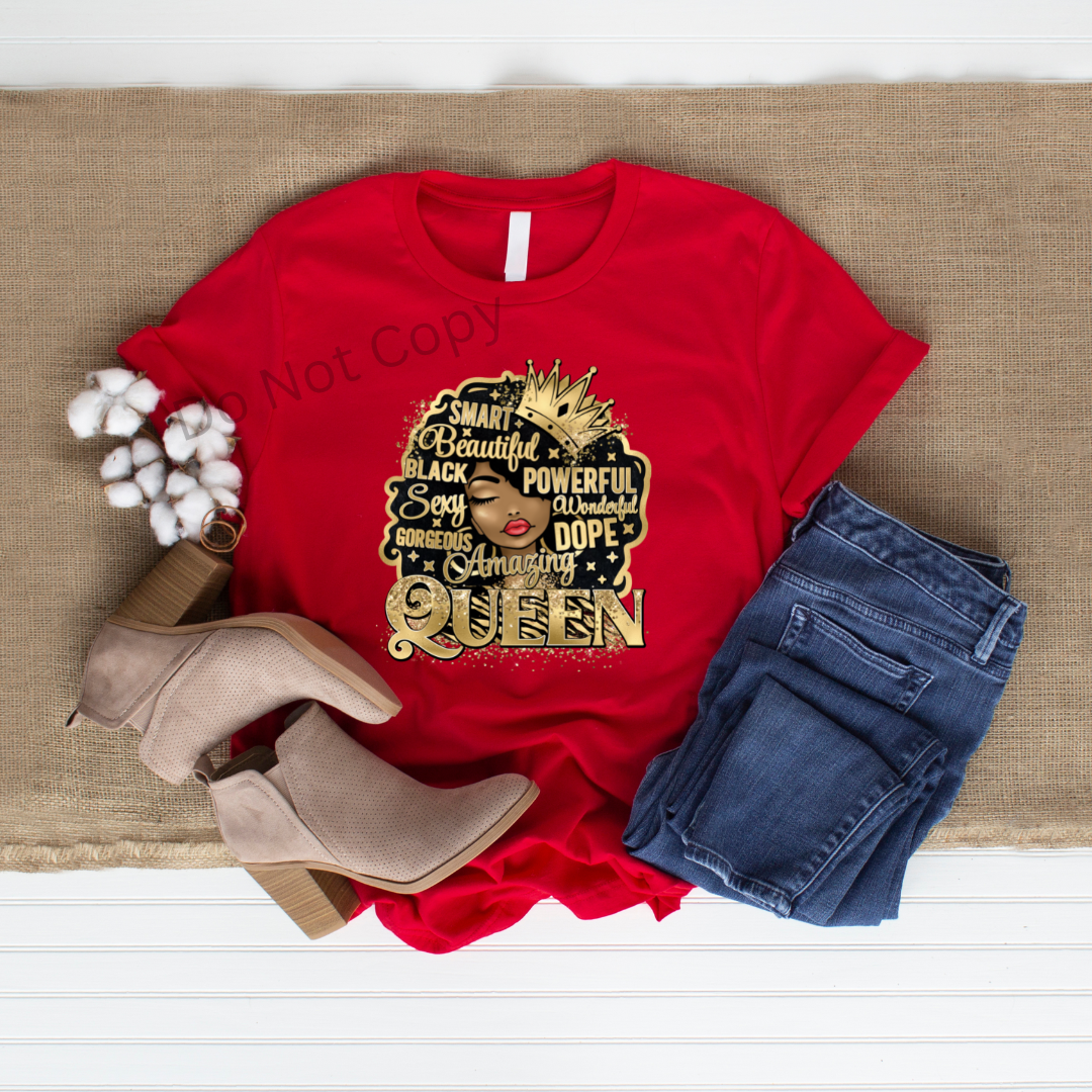 A red shirt with a gold DTF transfer that reads 'Queen' and has a graphic of a crown, accompanied by blue jeans and a pair of brown shoes.