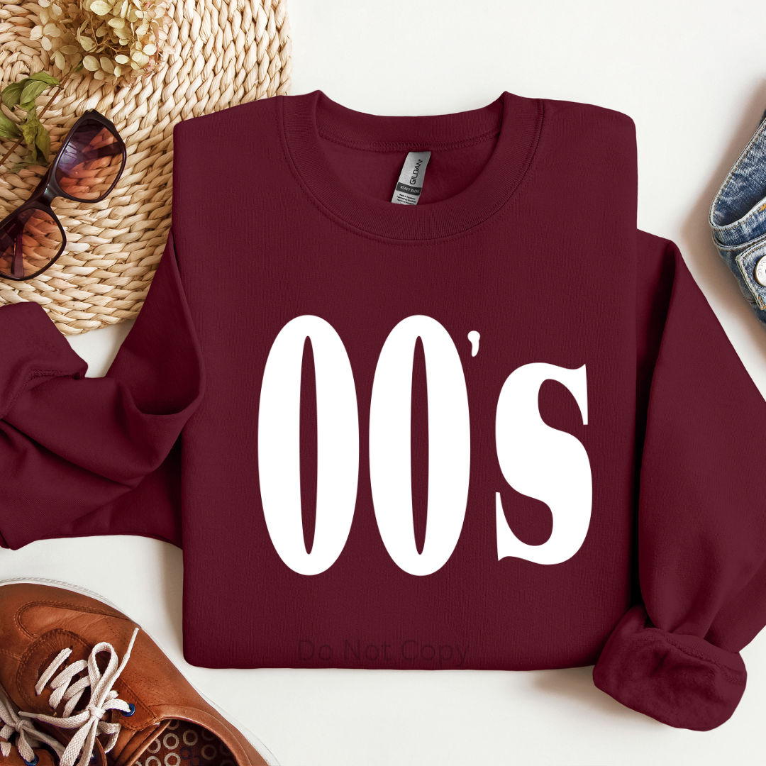 Maroon sweatshirt with '00s' text on a white surface with accessories.