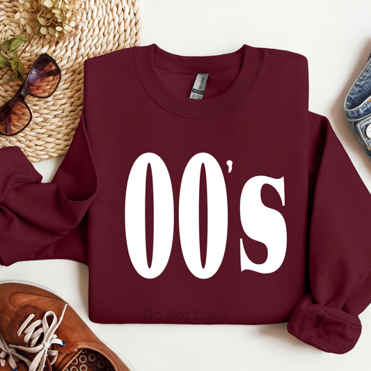 Maroon sweatshirt with '00s' text on a white surface with accessories.