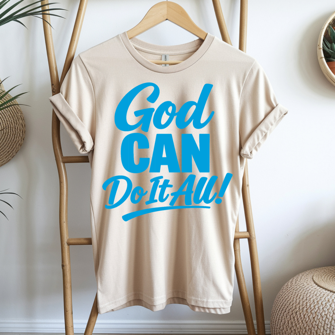 Beige t-shirt with blue text 'God CAN Do It ALL!' hanging on a wooden rack.