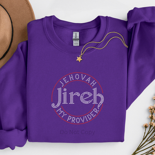 Purple sweatshirt with 'Jehovah Jireh My Provider' text, placed on a white surface with a hat and necklace.