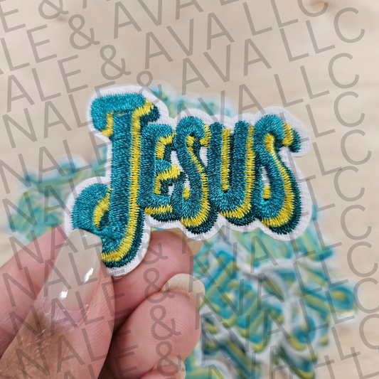 Embroidered patch with 'Jesus' text held by a hand on a branded background