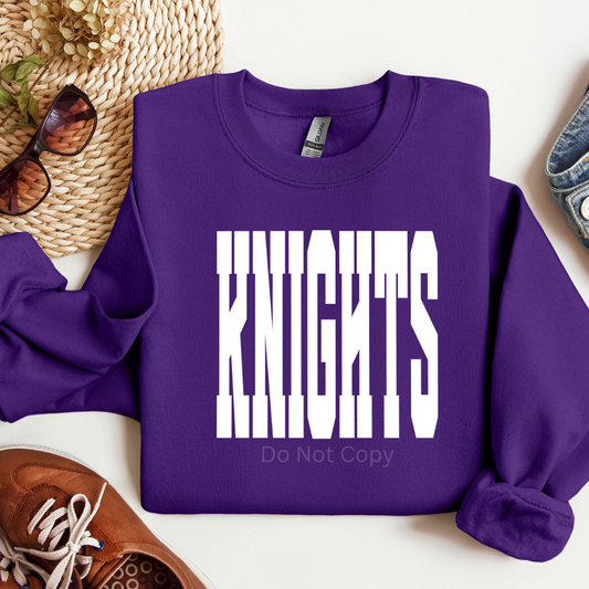 Purple sweatshirt with 'Knights' text on a white surface with accessories around