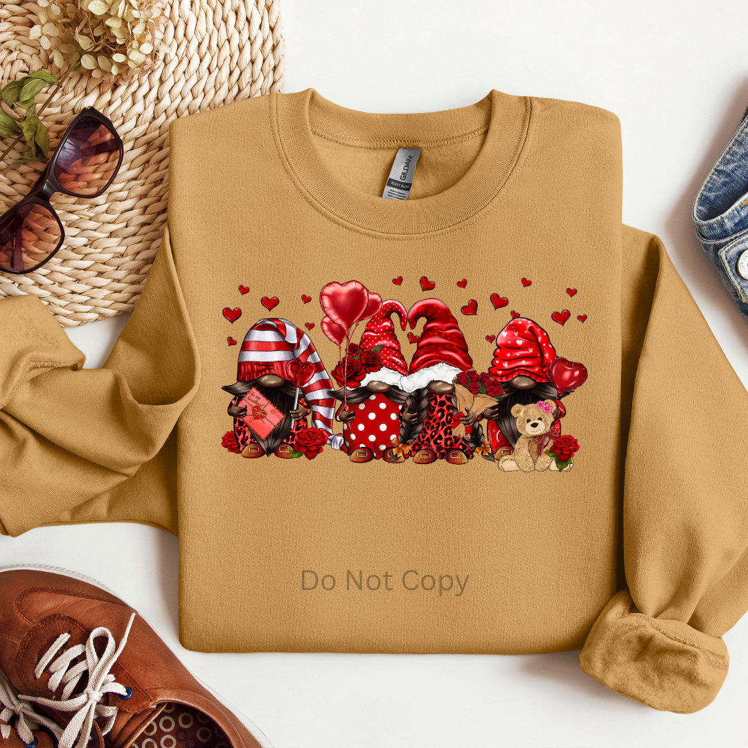 A sweatshirt with a transfer design featuring gnomes, hearts, and the text 'Love Day' on it, placed on a surface with sunglasses, a hat, and a shoe.