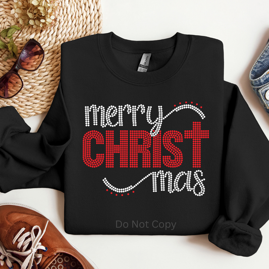 Black sweatshirt with 'Merry Christ Mас' text on a white surface with accessories.