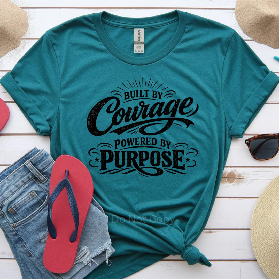 Teal t-shirt with motivational quote on a wooden surface with casual items.