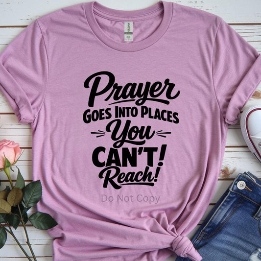 Pink t-shirt with motivational quote on a wooden surface with flowers and jeans.