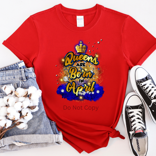 A red T-shirt with the text 'Queens are Born in April' surrounded by a crown and sparkles design, displayed alongside denim shorts and black sneakers.