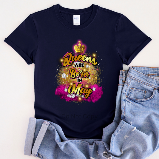 A navy blue T-shirt laid flat with a graphic transfer design that reads 'Queens are Born in May' accompanied by a crown and decorative elements.