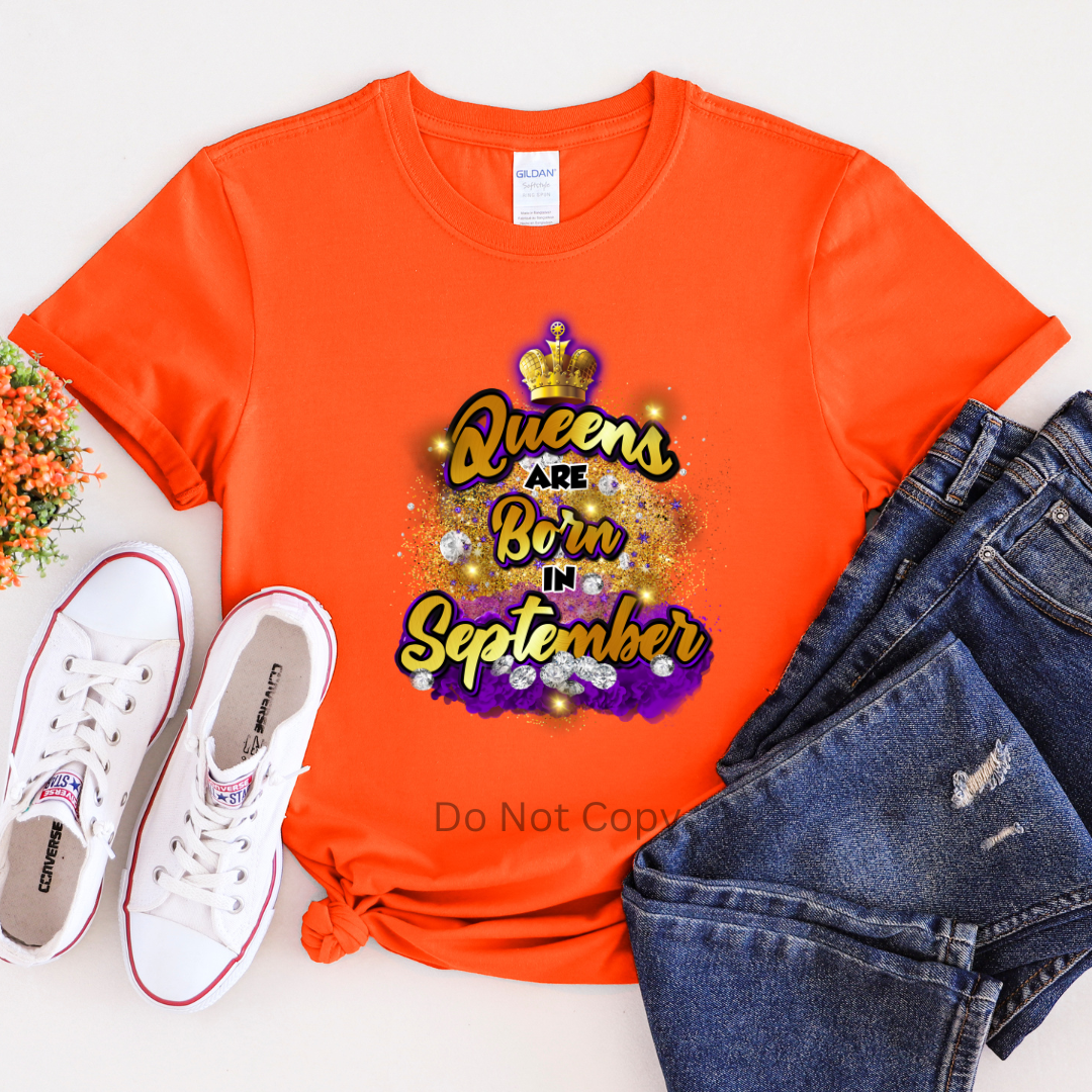 An orange T-shirt with the text 'Queens are Born in September' printed on it, displayed flat with a pair of jeans and white sneakers.