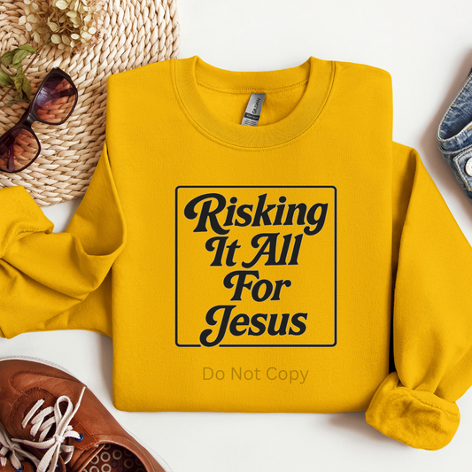 Yellow sweatshirt with 'Risking It All For Jesus' text on a white background