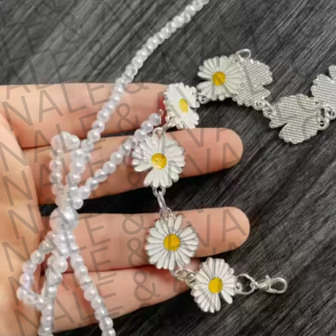 Bracelet with daisy flower charms held by a hand on a dark surface.