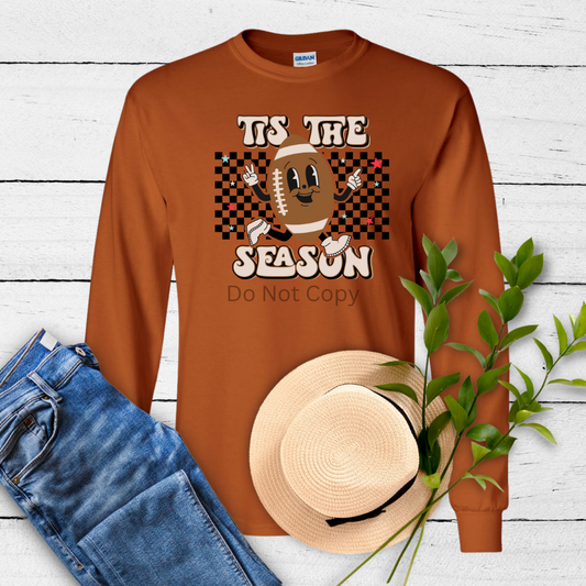 A long-sleeved brown T-shirt with a graphic transfer design depicting a football and the text 'Tis The Season'.