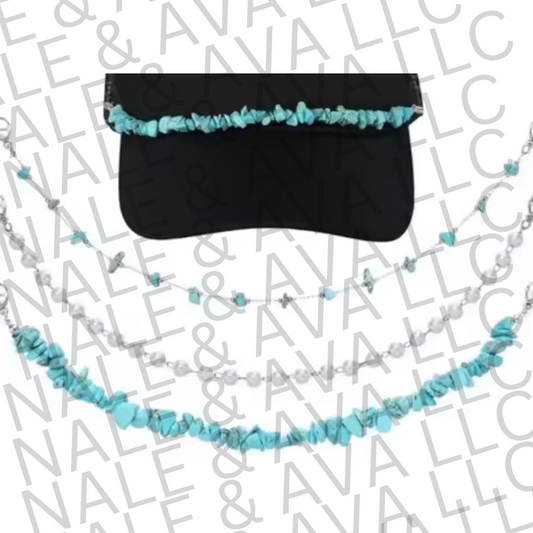 Black visor with turquoise and white beaded chain on a branded background