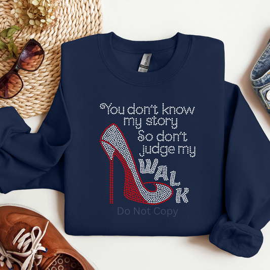 Navy blue sweatshirt with high heel graphic and text on a white surface with accessories.
