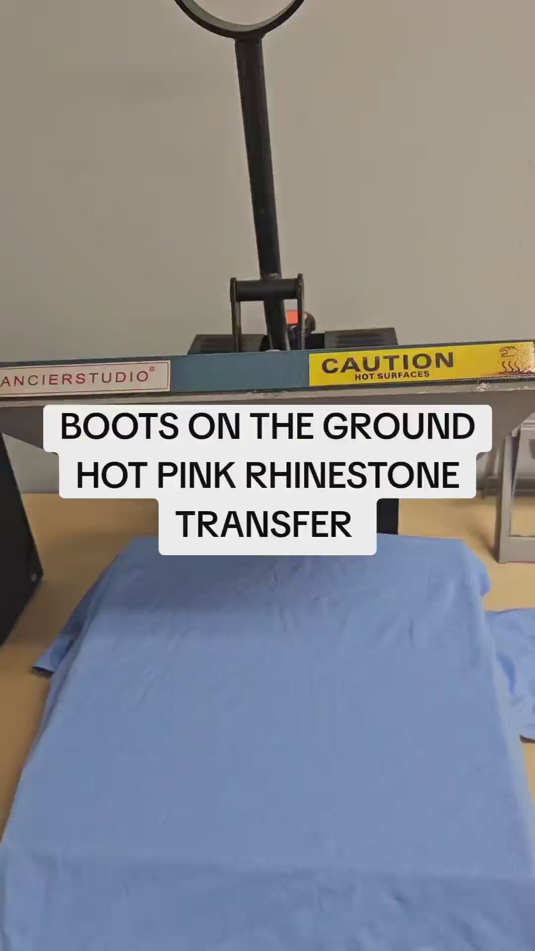 Video demonstration of how to apply a hot pink and silver rhinestone heat transfer to a cotton t-shirt using a commercial heat press at 330°F for 30 seconds.
