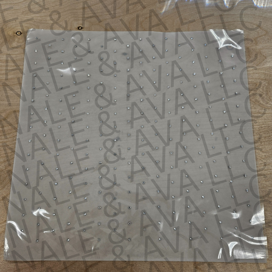 Sheet of decorative paper with clear rhinestones on a wooden surface