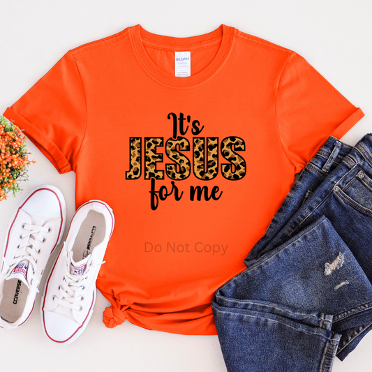 An orange t-shirt with the text 'It's Jesus For Me' printed on the front, accompanied by blue jeans and white sneakers.